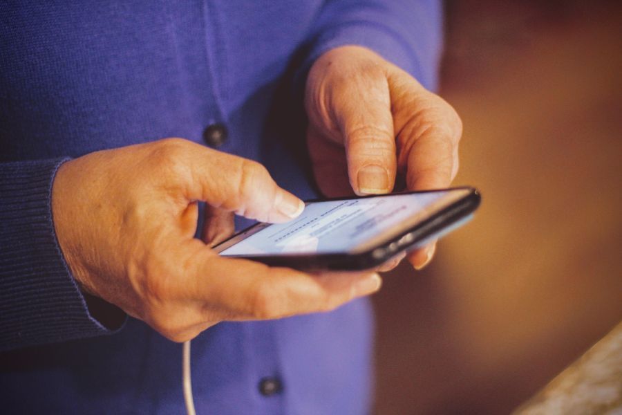 Mãos de idosa usando o celular para demonstrar a necessidade da acessibilidade digital para todos